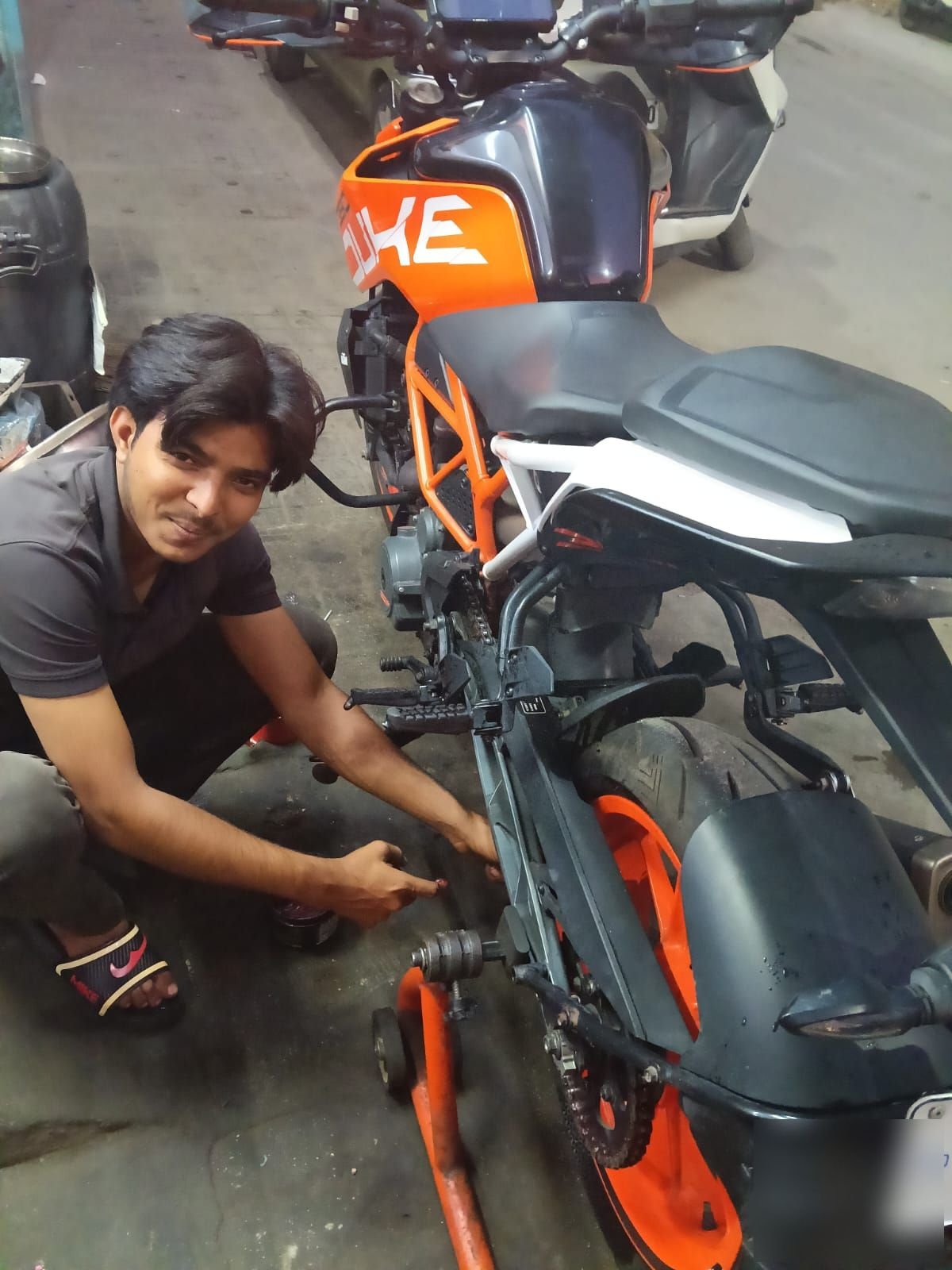 Drive-chain tensioning and paddock stand inspection on KTM Duke in Bangalore workshop